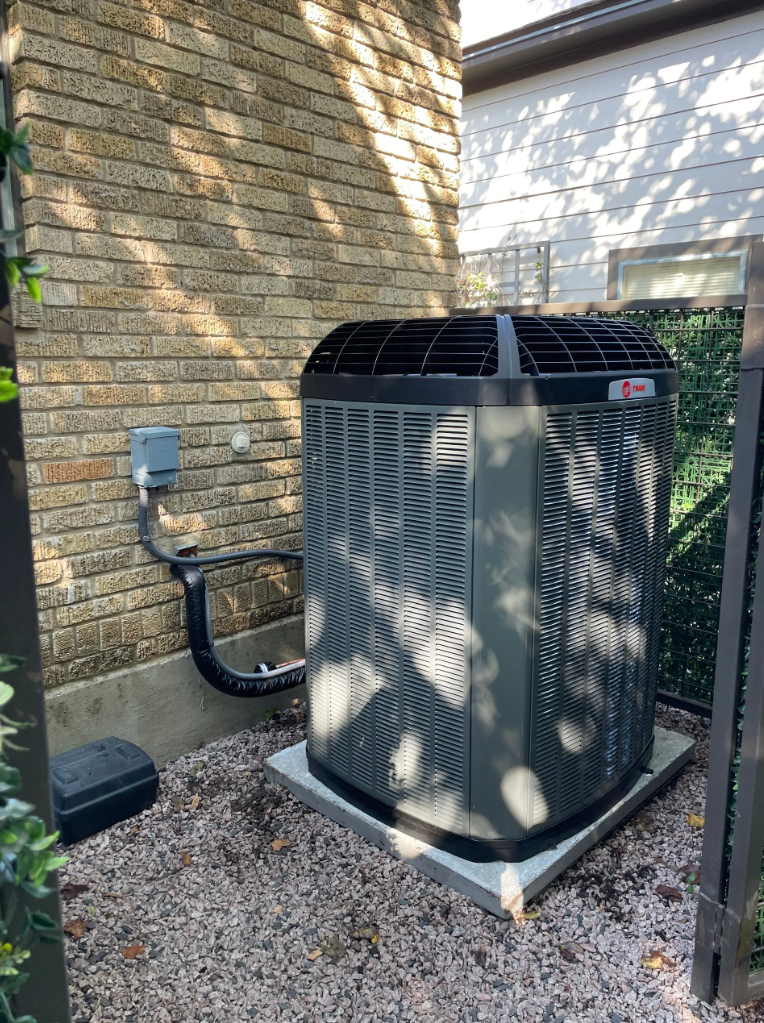 Trane outdoor condenser unit installed beside brick home