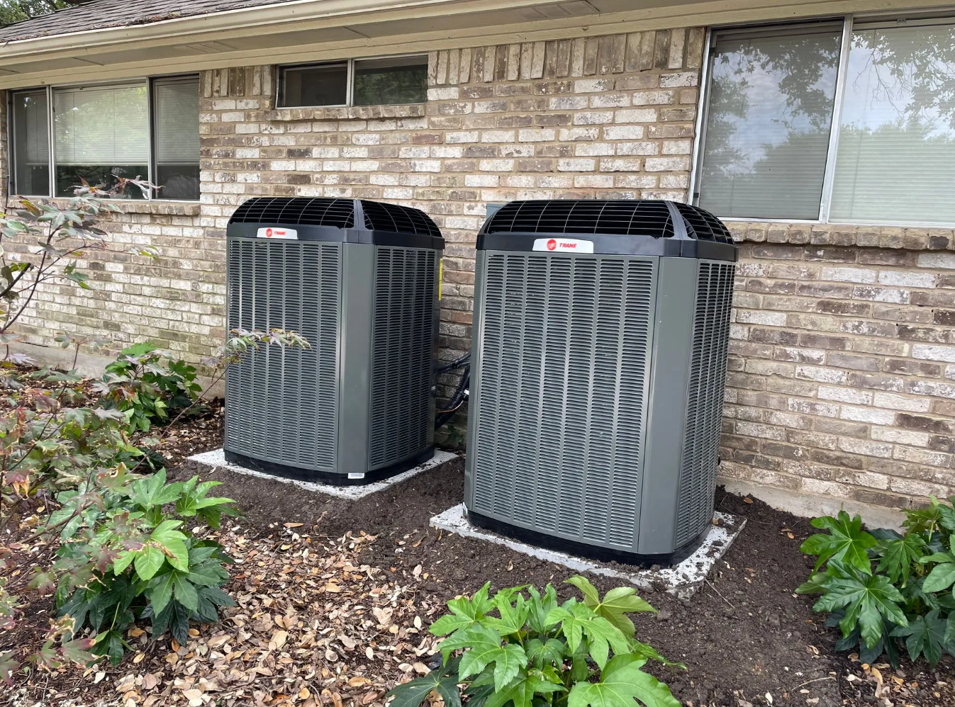 Twin Trane XV units installed against a stone home
